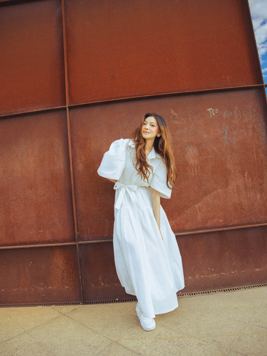 Abito bianco classico con colletto e taglio avvolgente, ideale per un’outfit senza tempo.