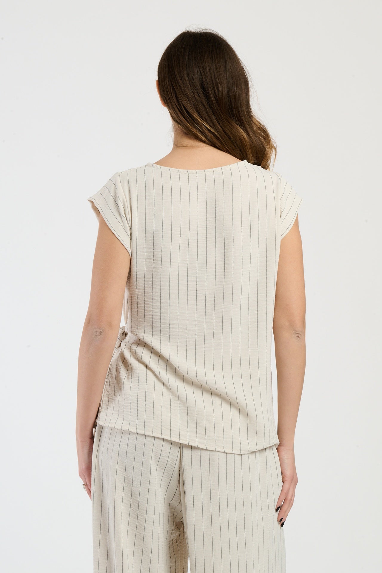 Donna in set beige con top a nodo, combinazione elegante per ogni occasione.