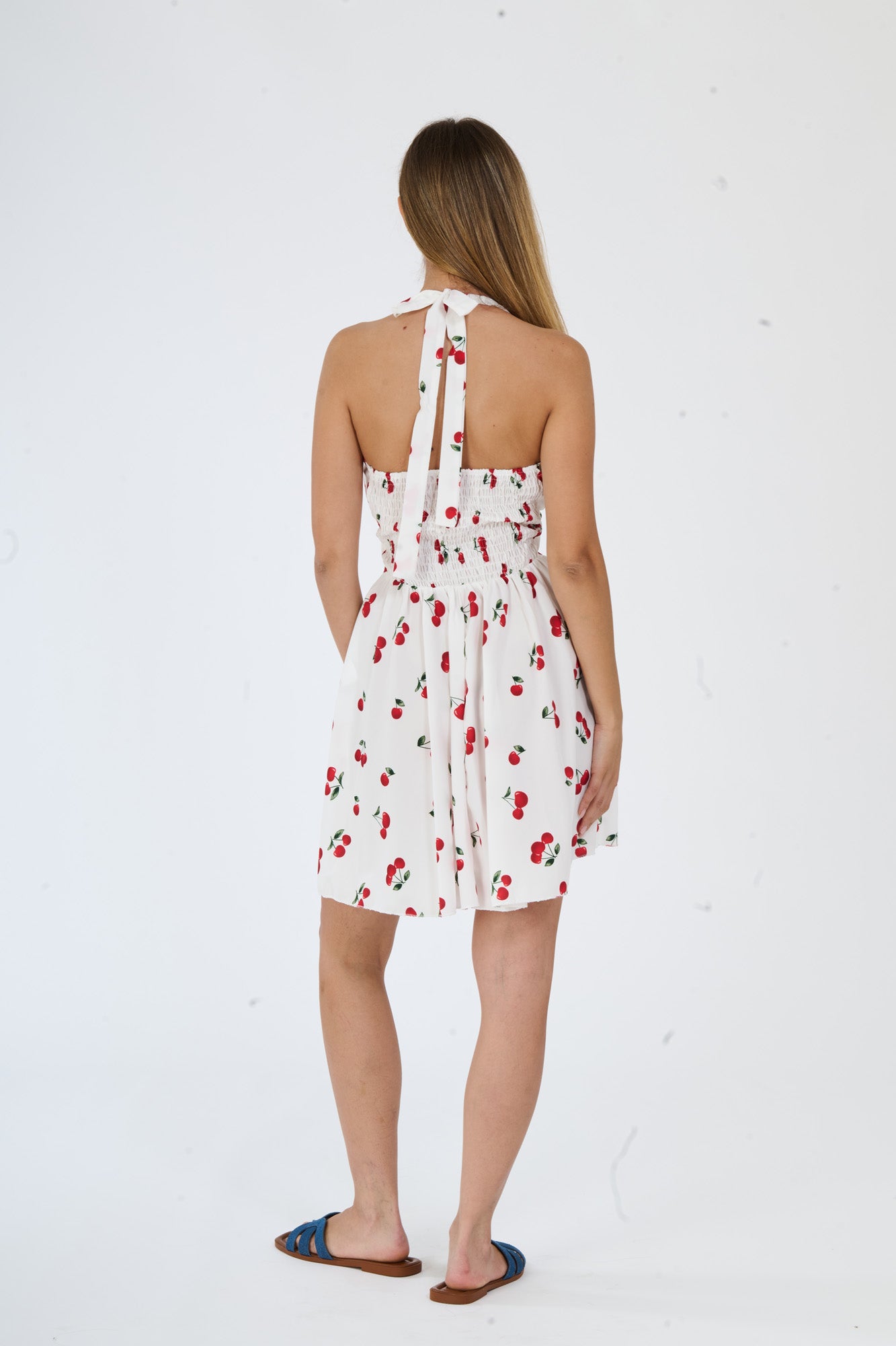 Donna in un abito bianco, senza maniche, spalline larghe e una bella fascia alla vita, il tratto lungo e elegante.