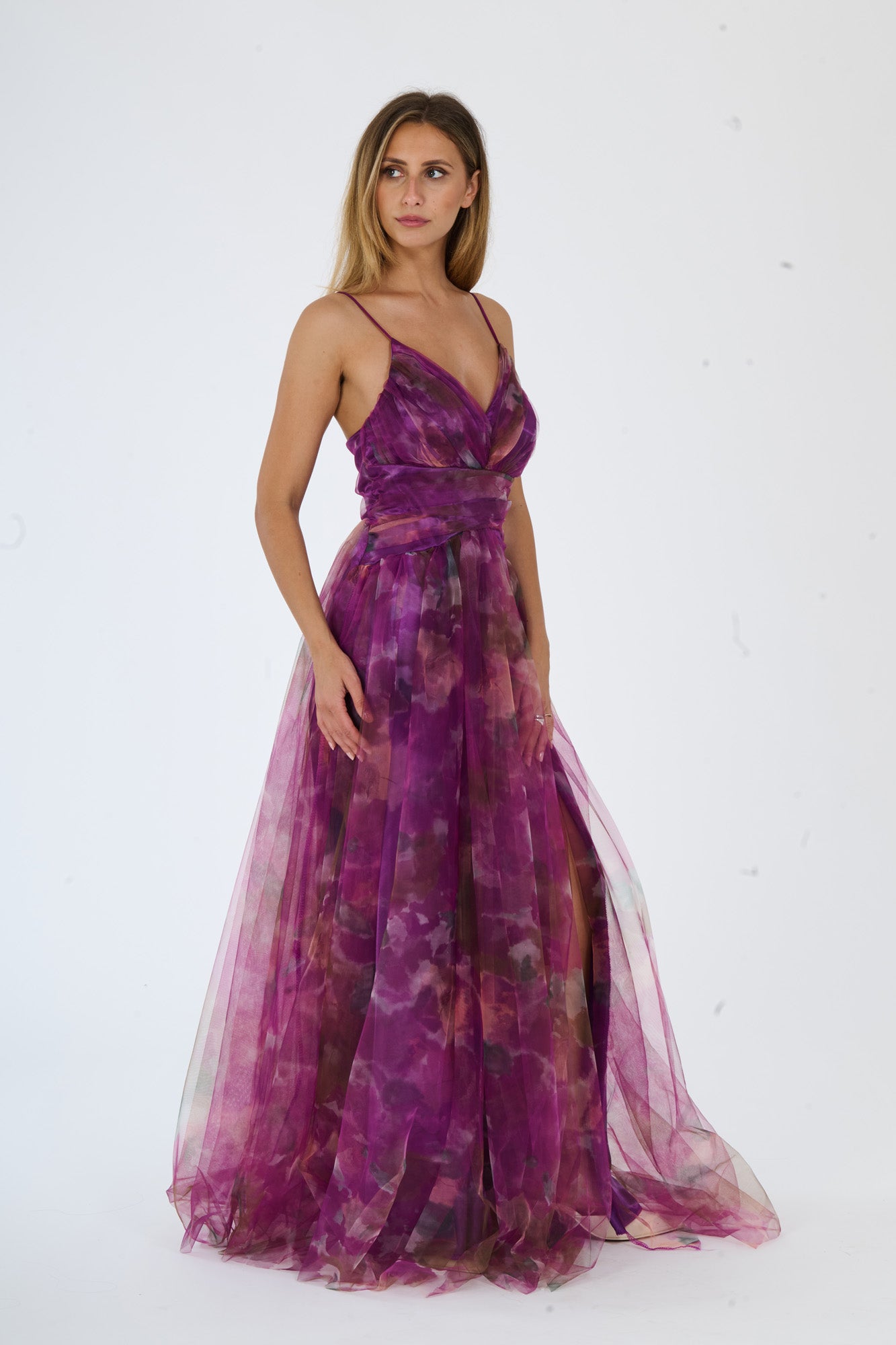 Modella in abito maxi viola con stampa floreale, spalline sottili e apertura laterale