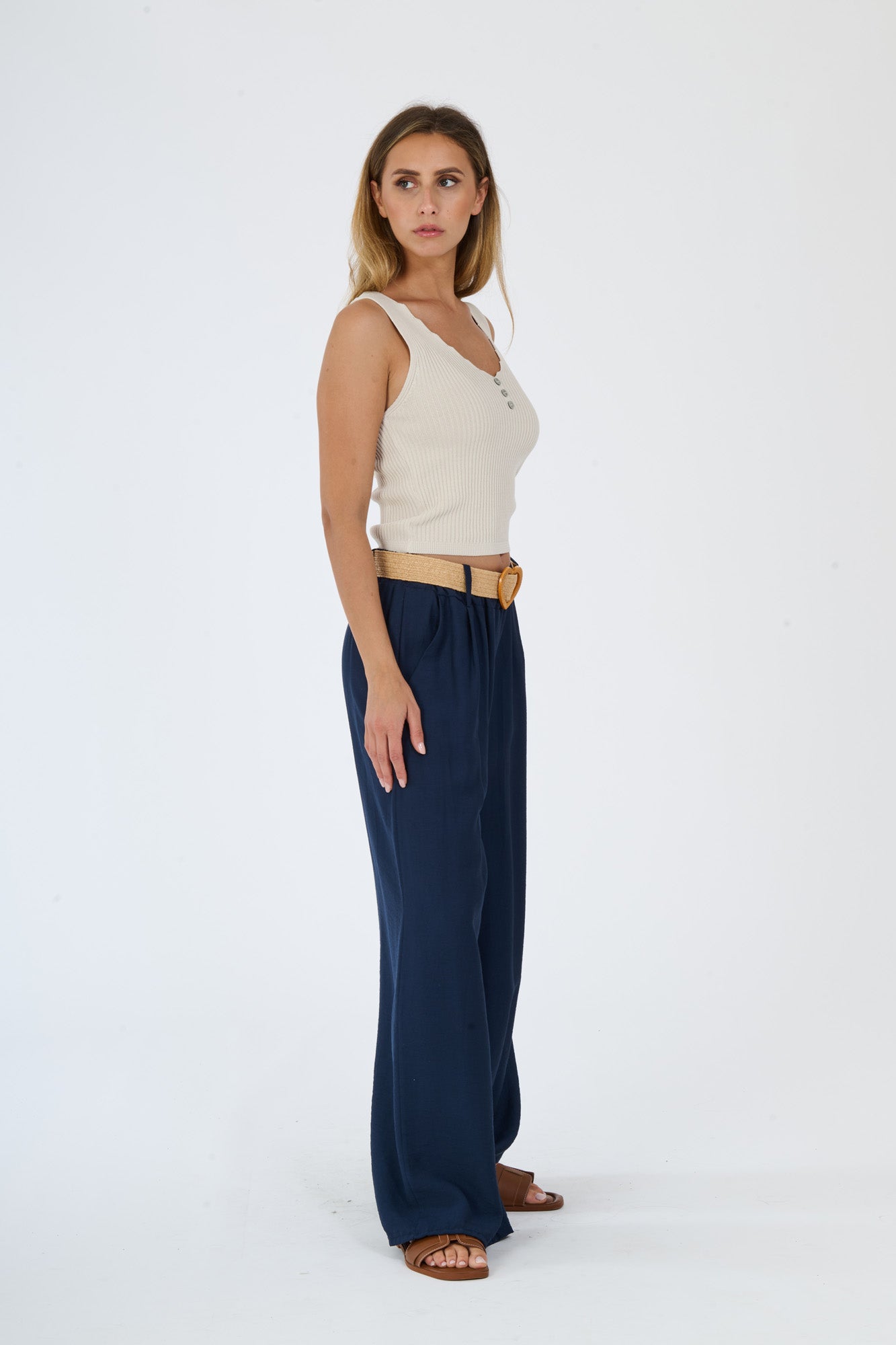 Top beige senza maniche e pantaloni larghi bianchi, un abbinamento che trasmette eleganza e semplicità.