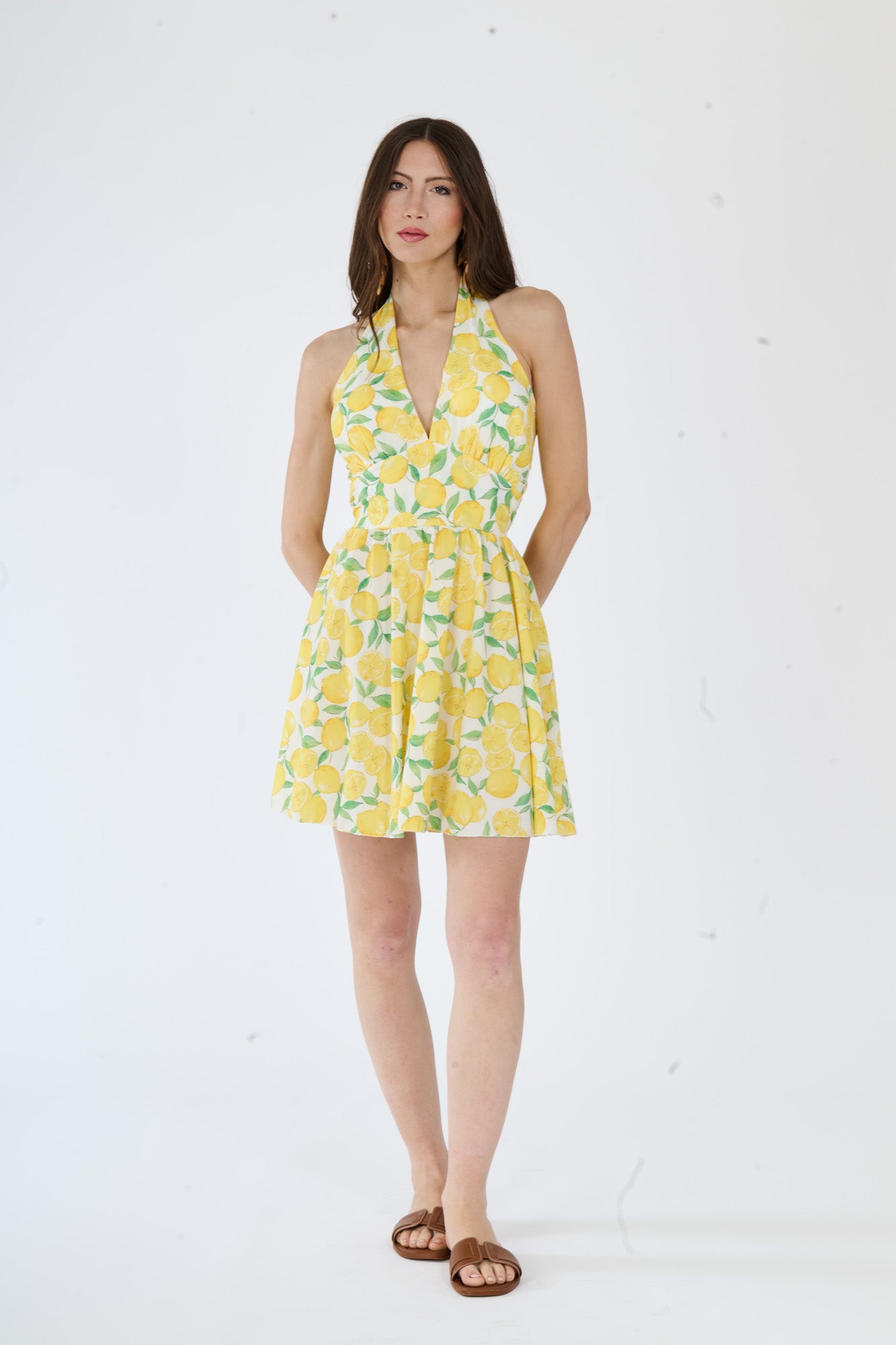 Modello indossa un abito giallo moderno, spalline larghe, una cintura sottile e una lunga gonna fluida.