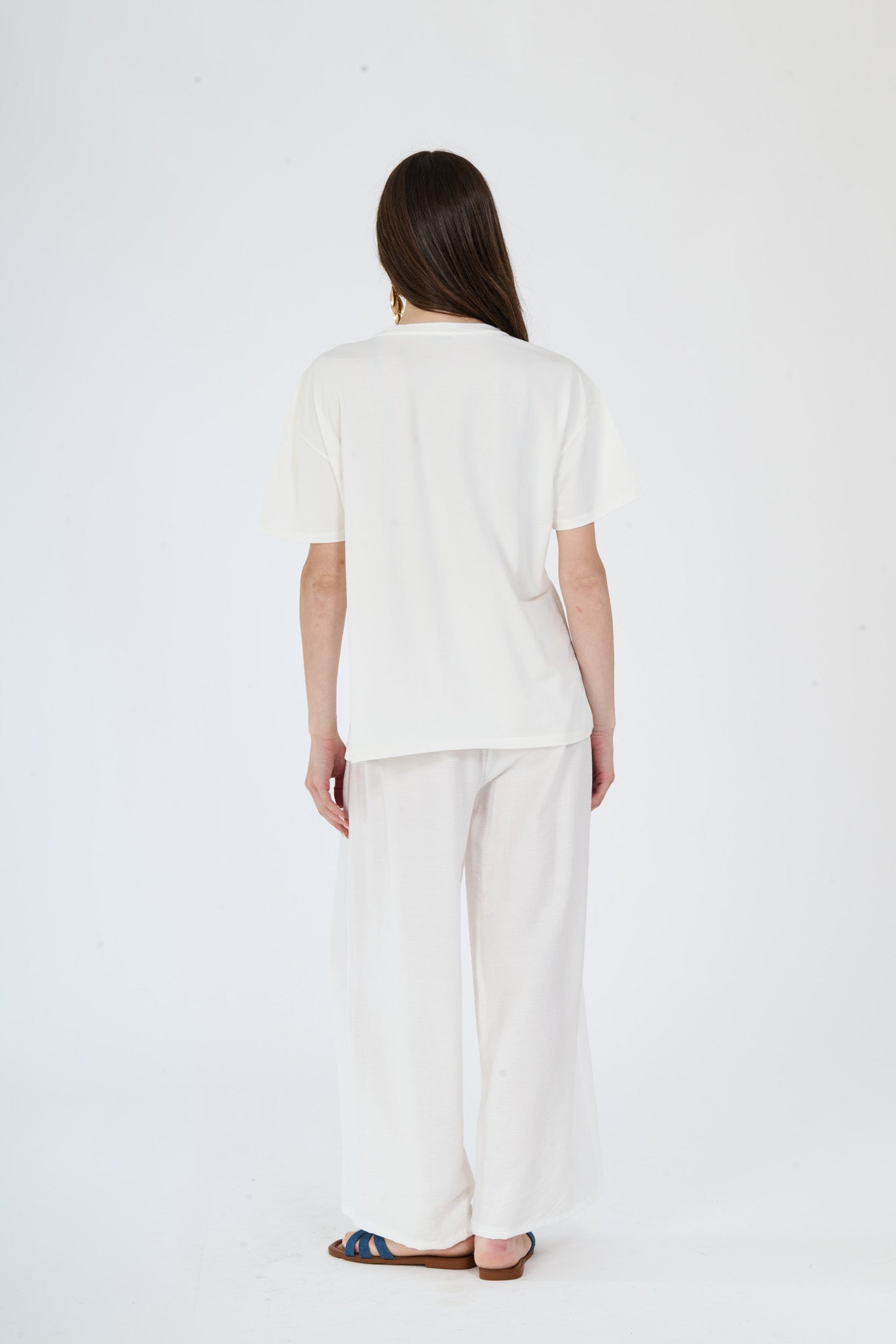 Outfit bianco e scuro: t-shirt beige e pantaloni larghi scuri su una figura