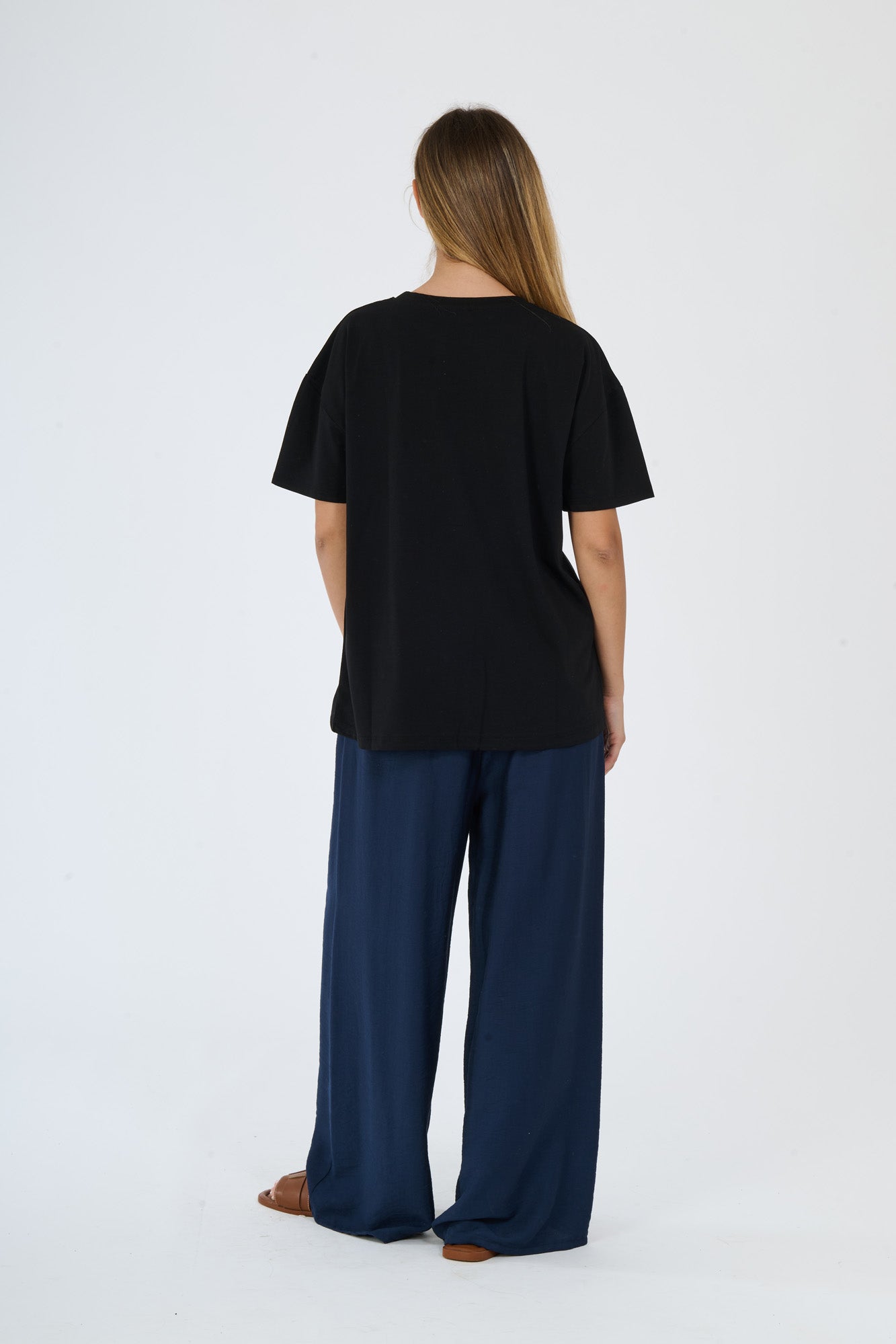Outfit nero e scuro: t-shirt beige e pantaloni larghi scuri su una figura