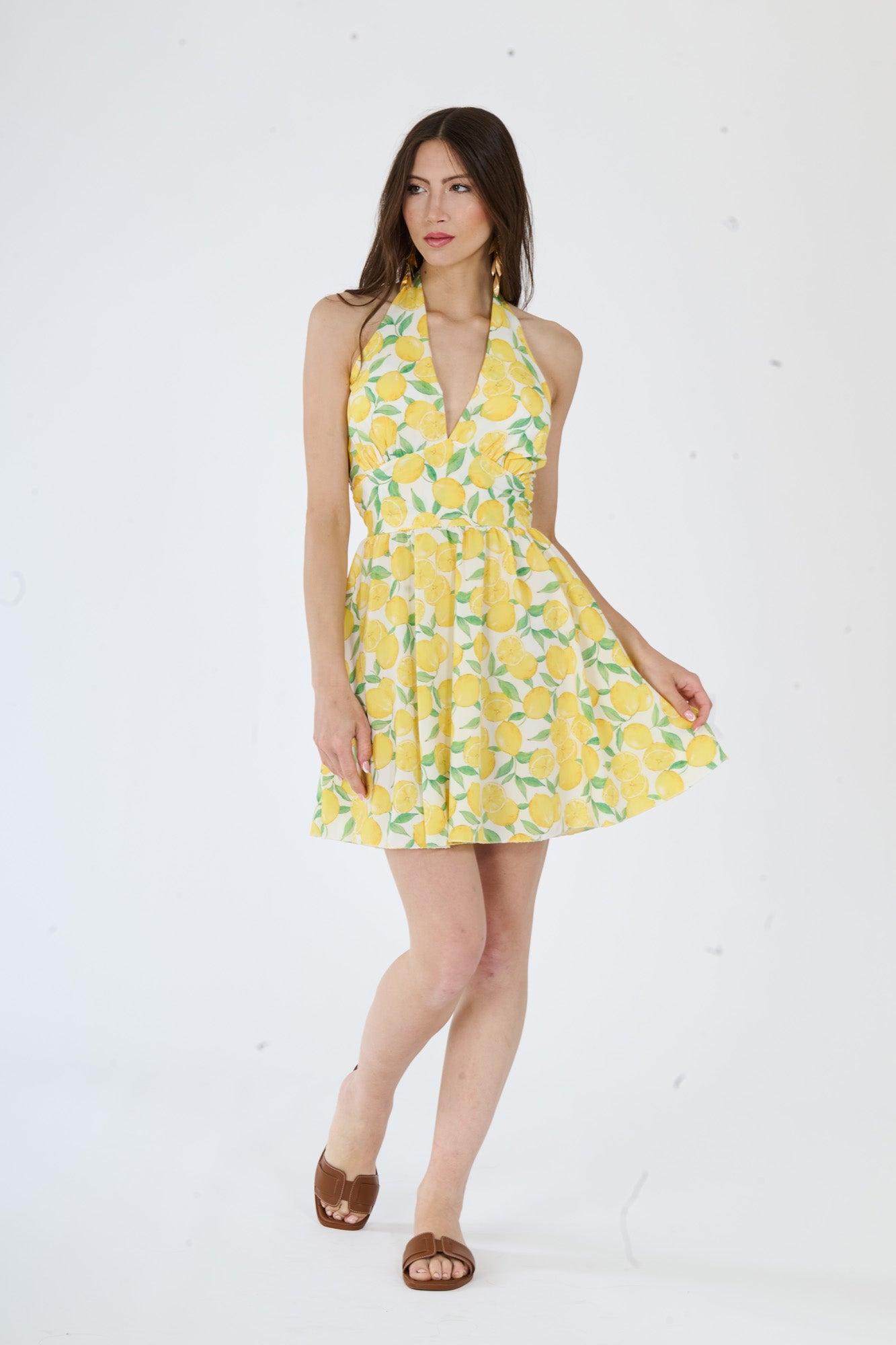 Vestito giallo senza maniche, spalline larghe e una fascia alla vita, con un taglio lungo e fluido.