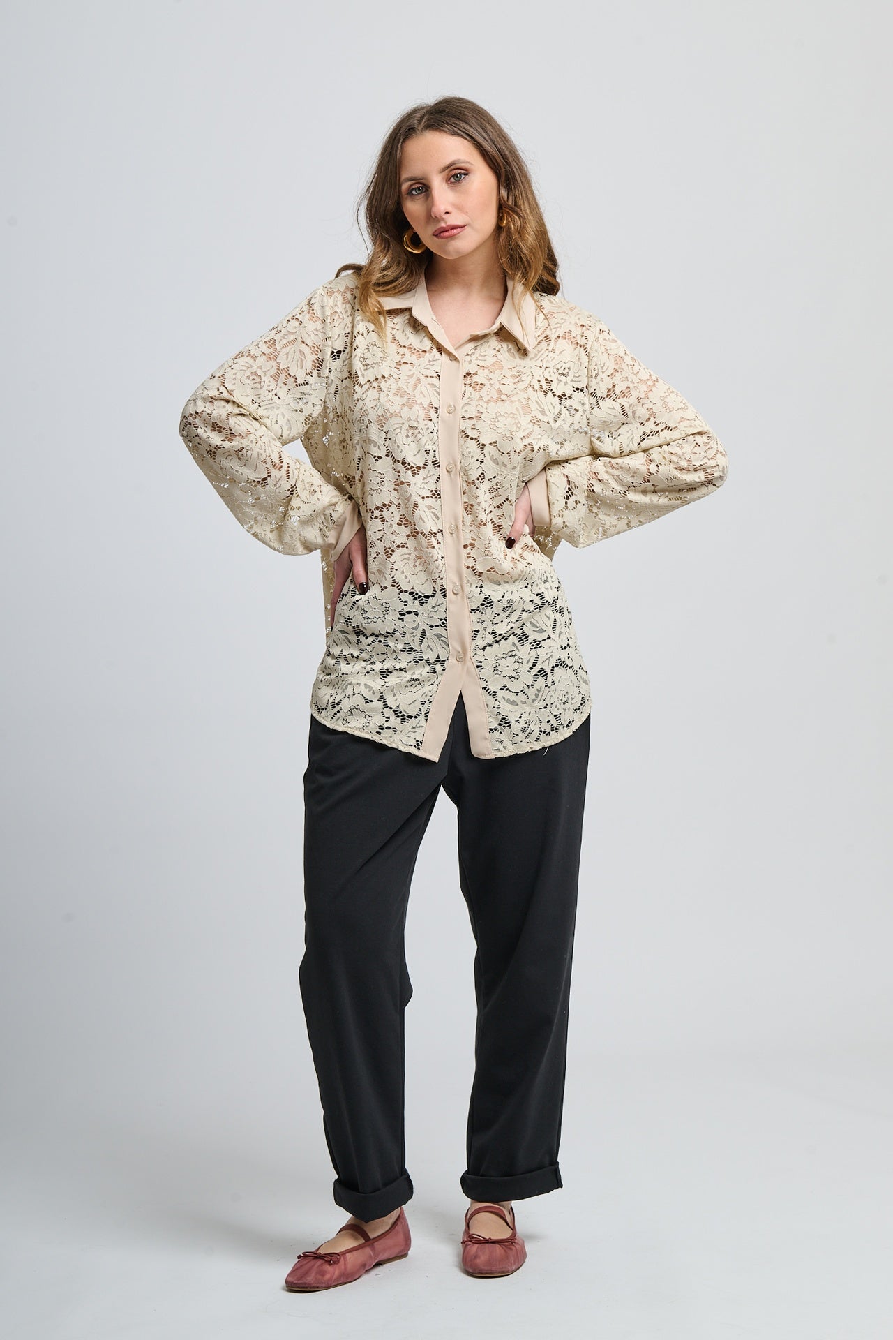 Camicetta beige con motivi, collo camiciera e maniche lunghe, abbinata a pantaloni neri.