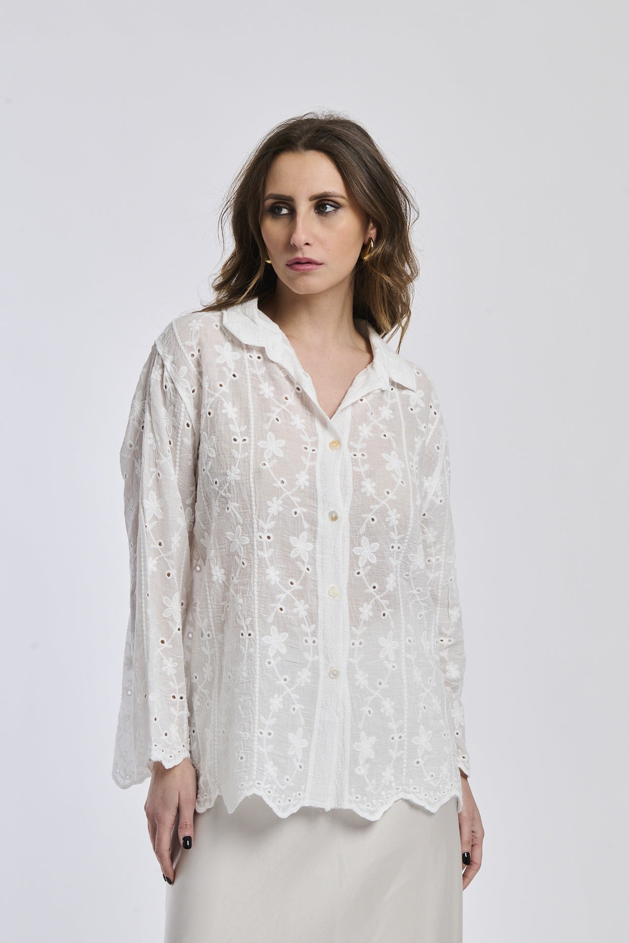 Donna indossa camicia bianca a maniche lunghe, colletto a bottone, con dettagli ricamati