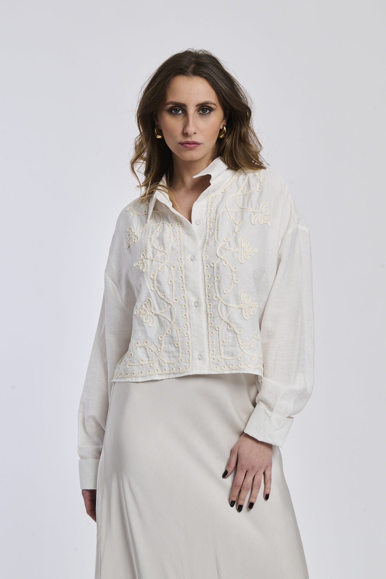 Una donna indossa una camicia a righe blu scuro e bianco, con maniche lunghe arrotolate e un nodo alla vita,
