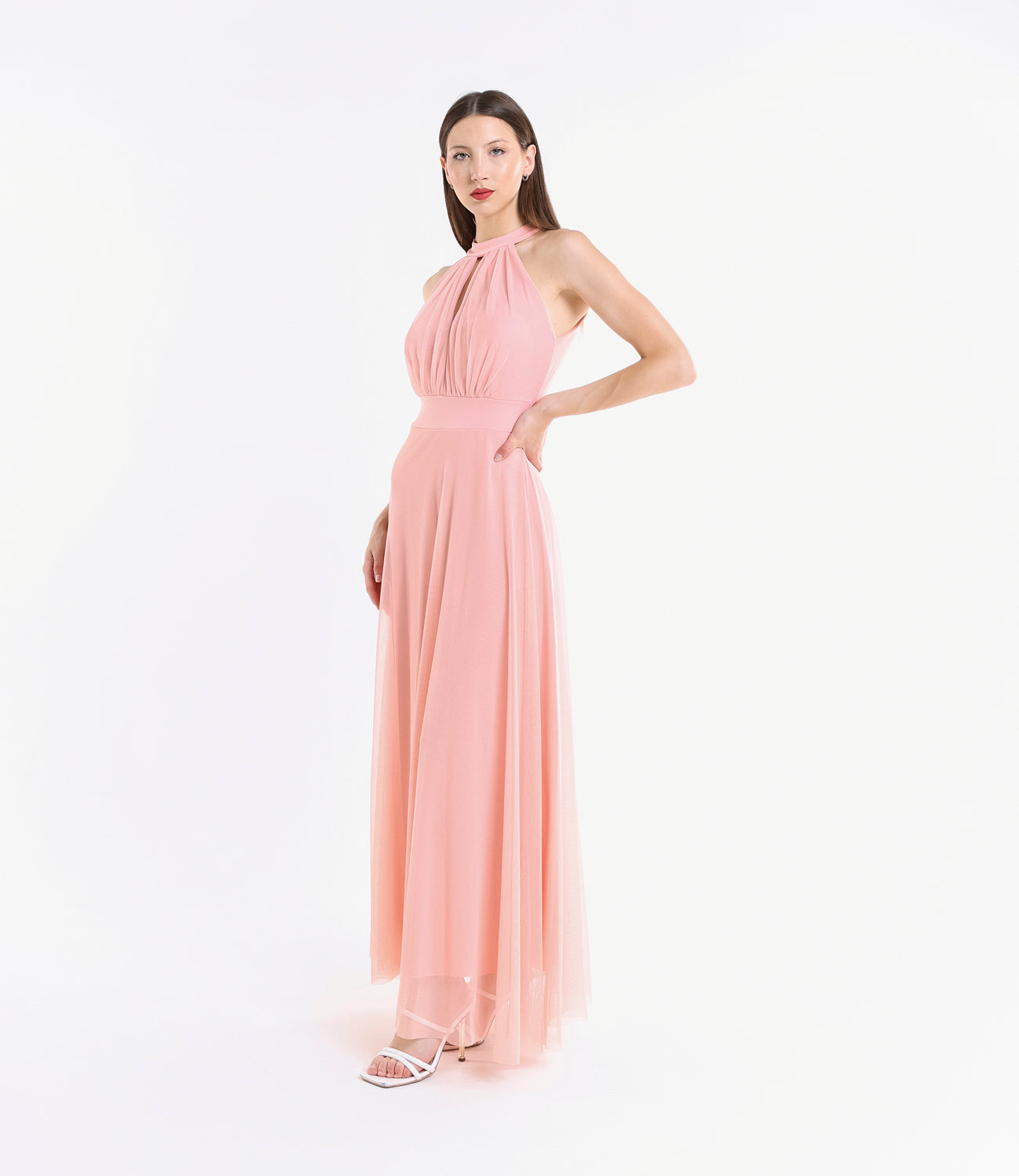 Abito rosa in tulle, colletto alto, posa femminile accanto a pianta verde