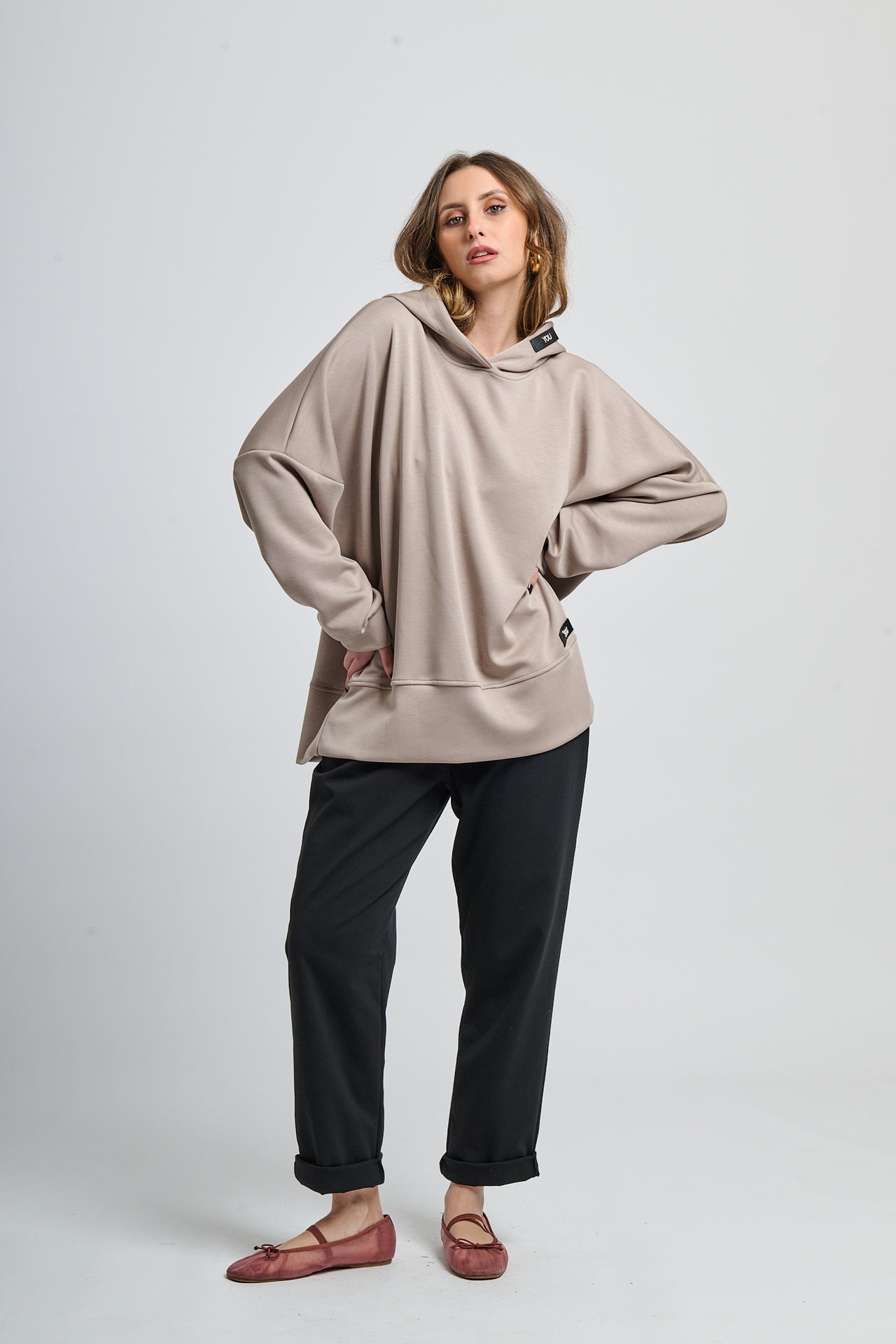 Outfit con felpa fango con cappuccio e pantaloni neri, contrasto caldo