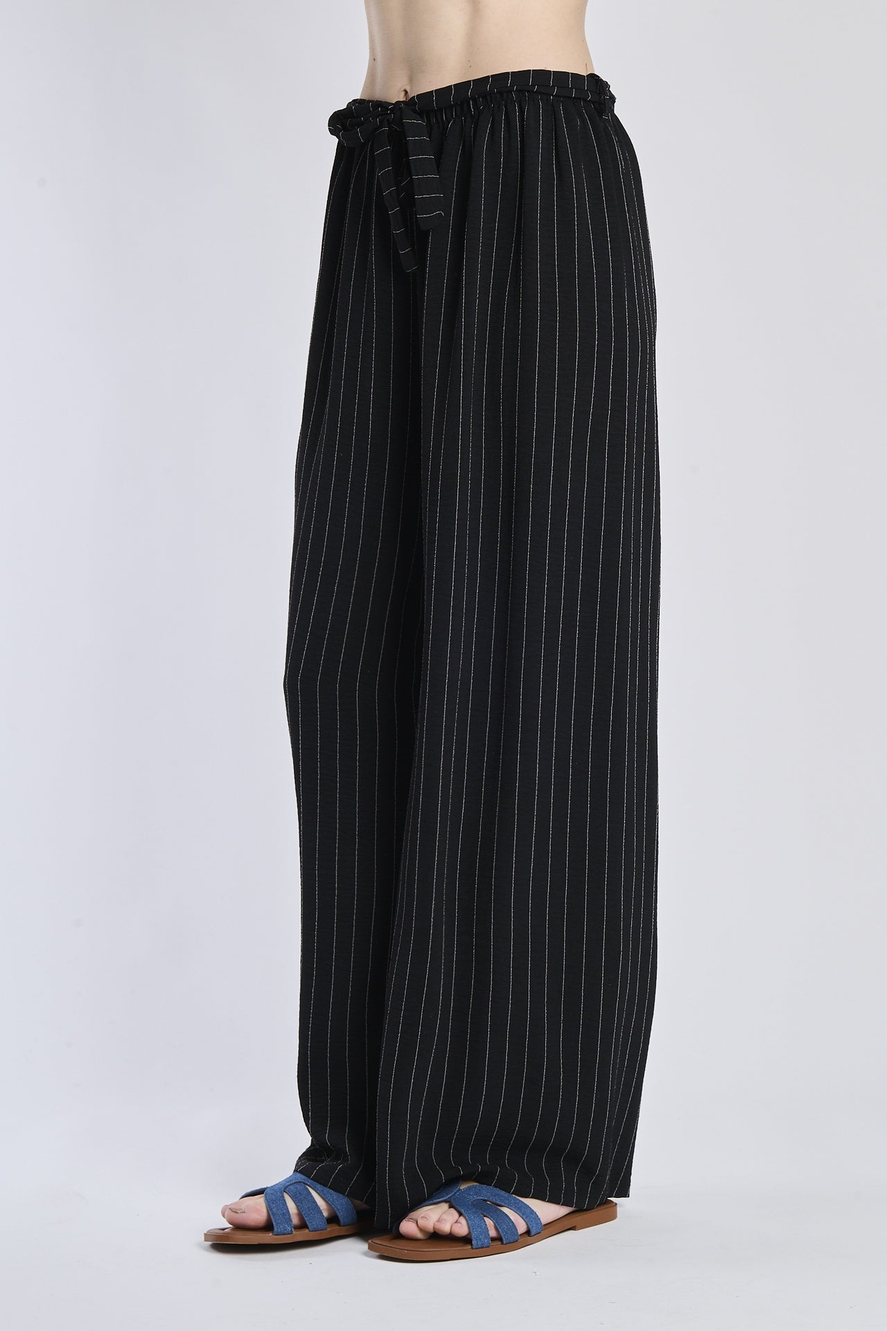 Pantaloni fluido neri, taglio ampio, nodo decorativo in vita, adatti per un outfit elegante.