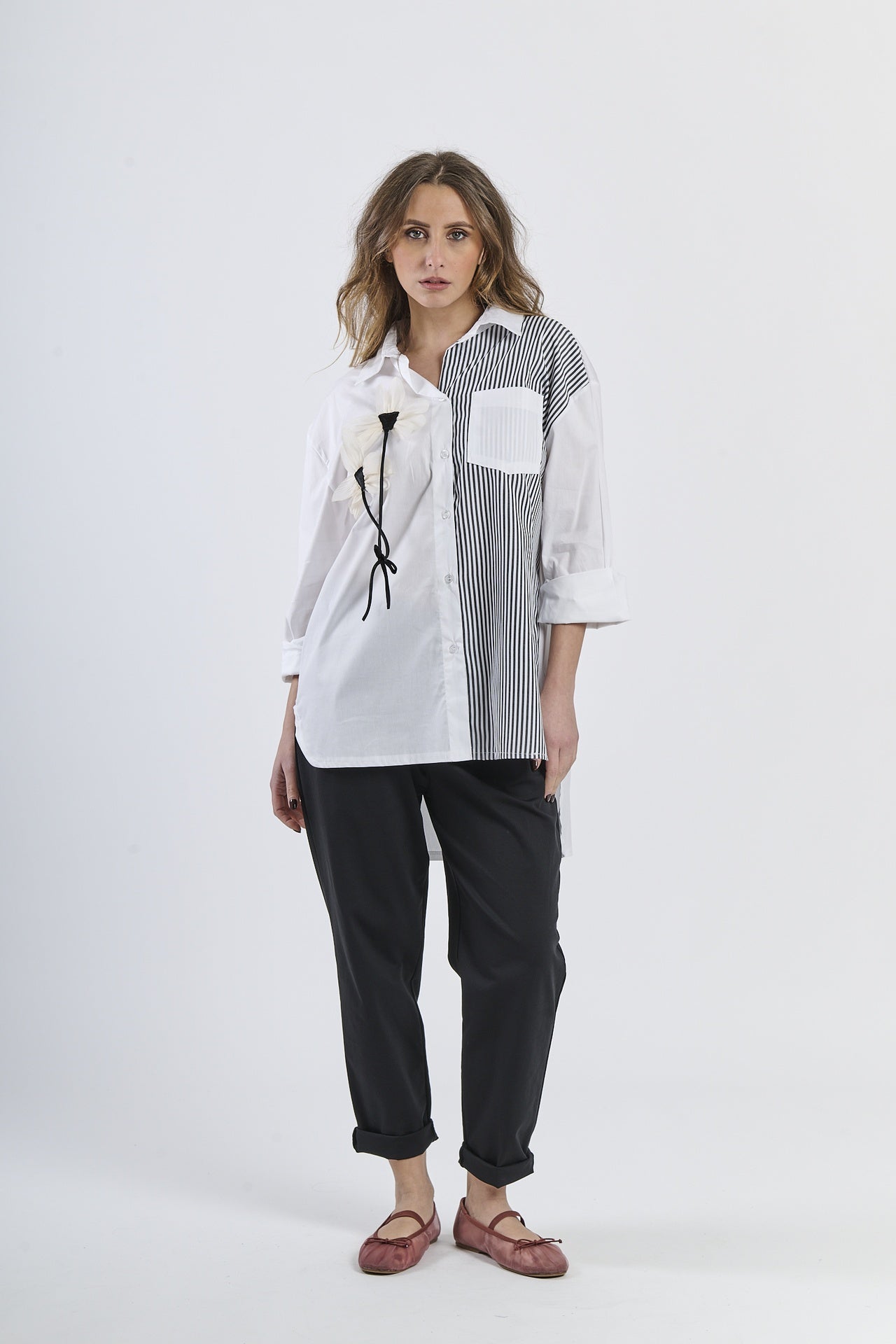Look fashion con camicia nero bicolor a righe, colletto classico, maniche a 3/4 e decorazione floreale, abbinata a pantaloni scuri