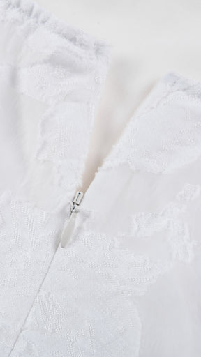 Abito corto elegante a spalline sottili con scollo a fascia, tessuto jacquard floreale e dettaglio a croce sul retro
