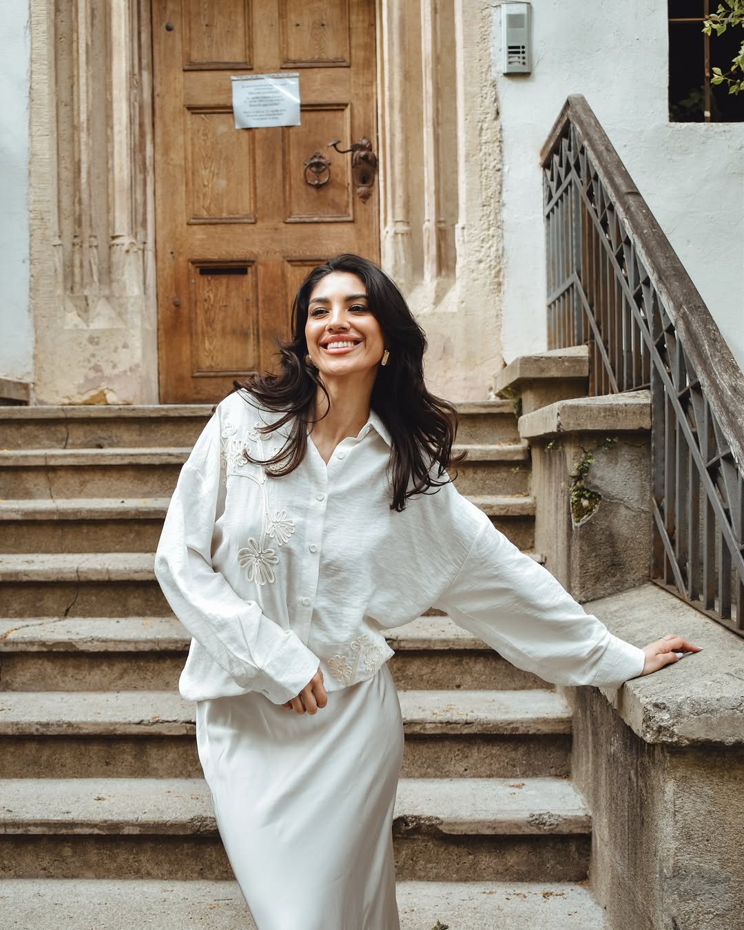 Una donna indossa una camicia di colore blu scuro intenso, con maniche lunghe e un leggero piegamento ai polsi,