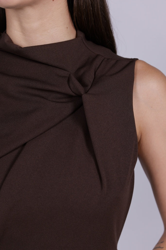 Abito da donna marrone, senza maniche, midi, nodo sul petto, estetica elegante e calda.