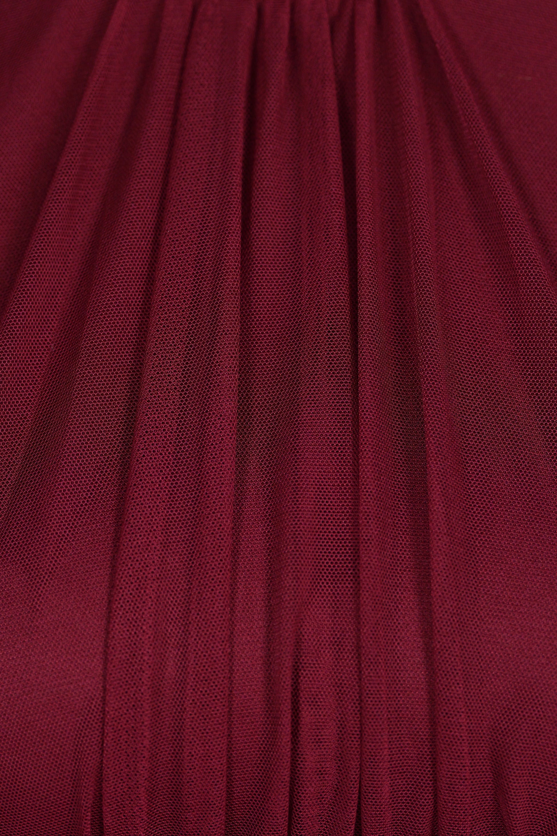 Abito da donna vino, collo alto a imbarcatura, gonna lunga, foulard in tulle, estetica elegante e intensa.