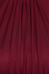 Abito da donna vino, collo alto a imbarcatura, gonna lunga, foulard in tulle, estetica elegante e intensa.