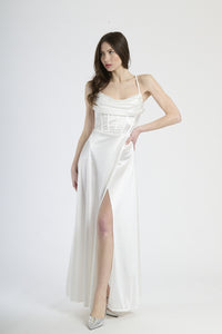 Abito lungo bianco in raso, con spalline sottili, colletto drappato e spalanca laterale.