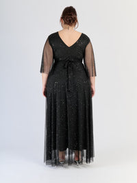 Abito nero da cerimonia, flusso e con maniche traslucide, incarna il lusso nero.