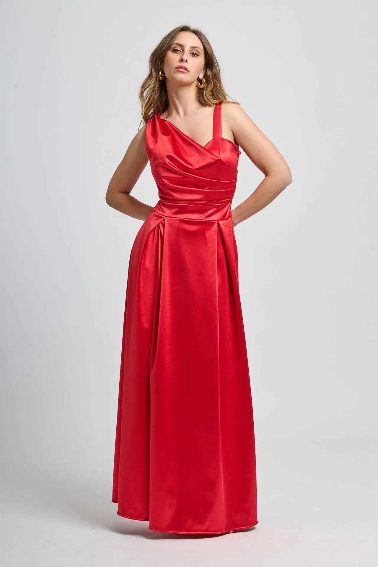 Abito rosso in tessuto satinato, spalliera singola e drappeggiato sul busto.