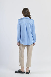 Camicia azzurra fluida e lucida, maniche lunghe e design classico.