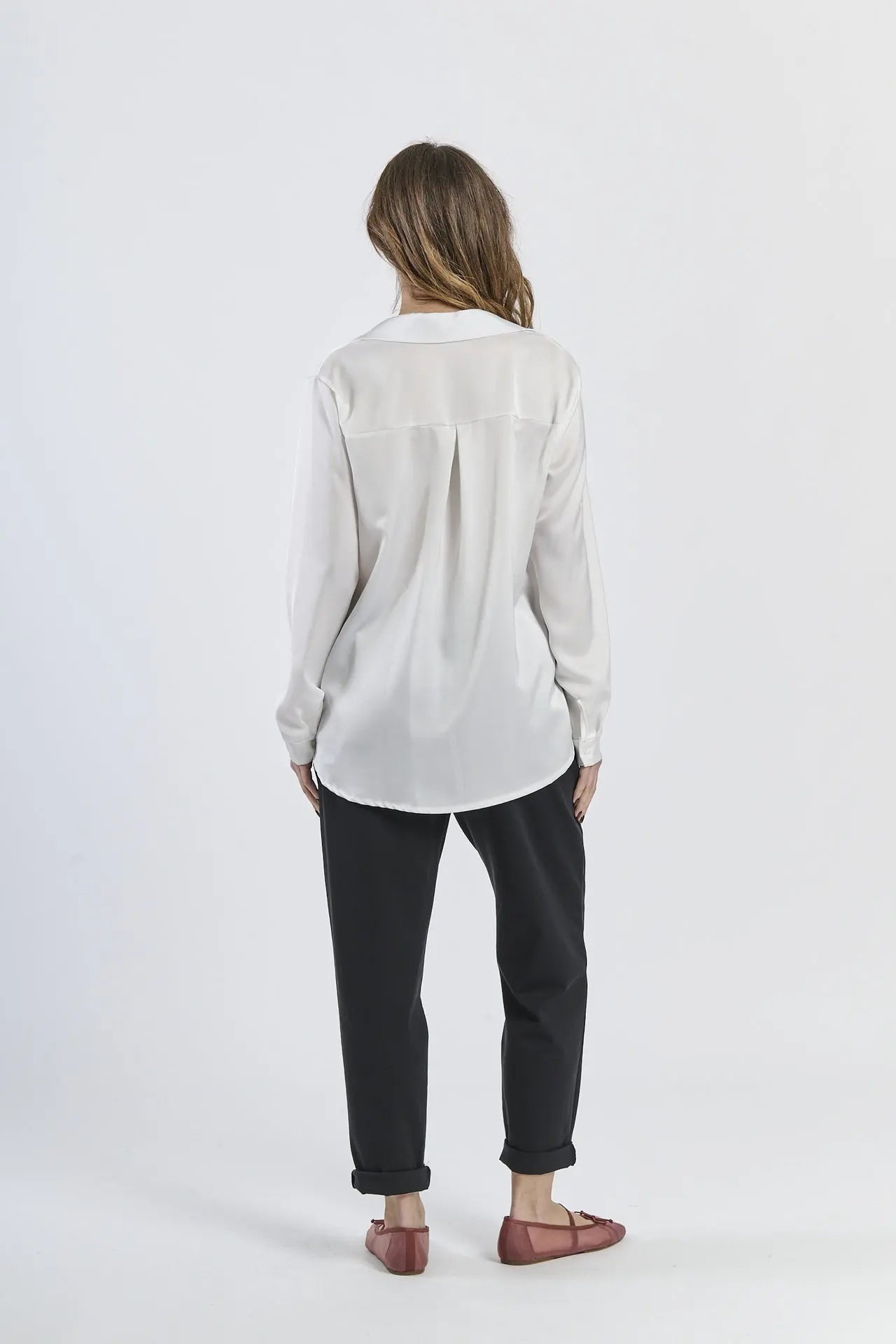 Camicia bianca fluida e luminosa, maniche lunghe e design minimalista.