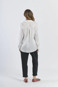 Camicia bianca fluida e luminosa, maniche lunghe e design minimalista.