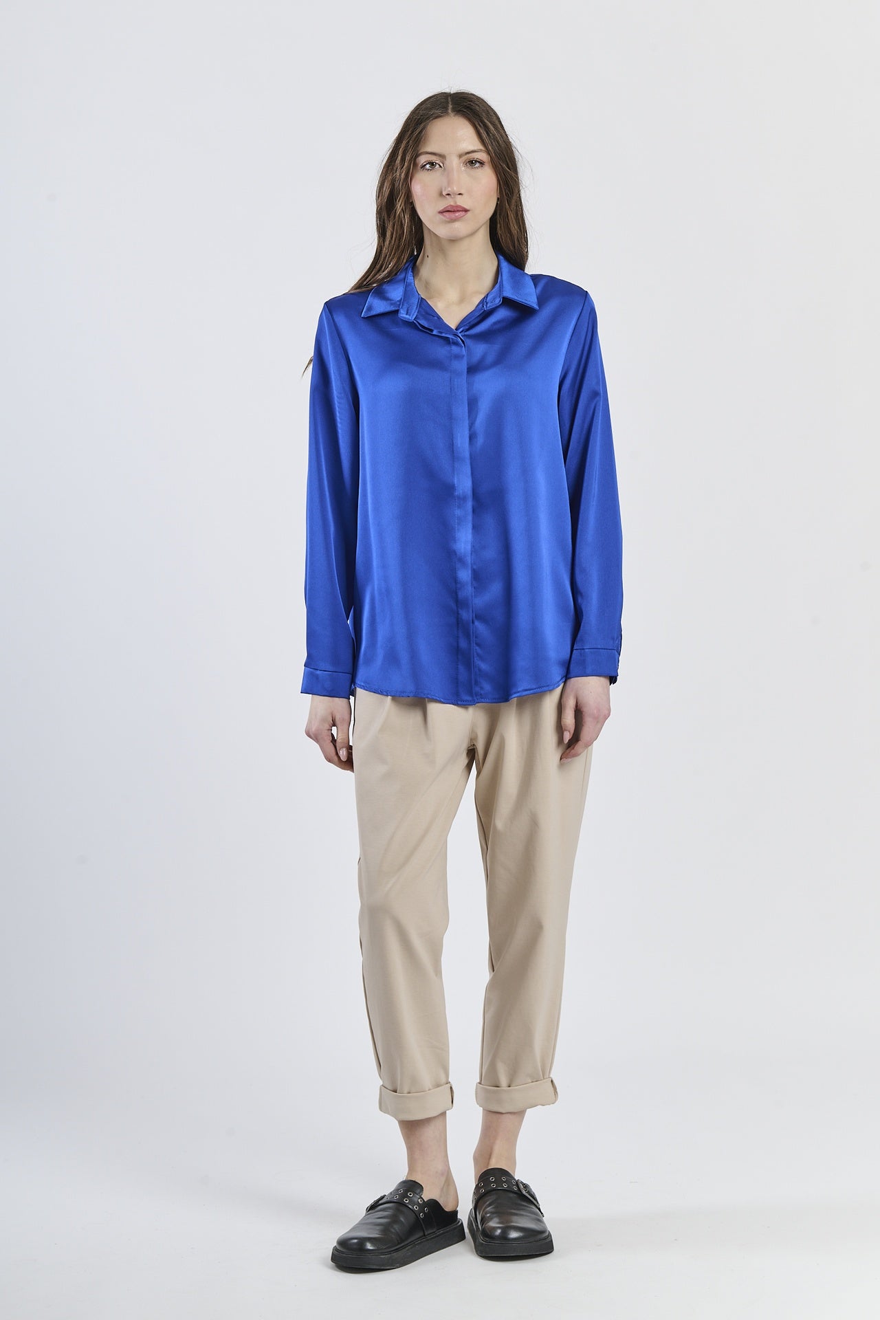 Camicia bluette in seta con colletto, abbinata a pantaloni beige.