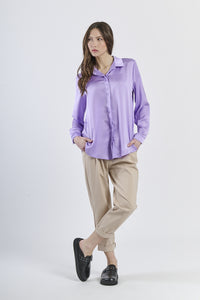 Camicia lilla in seta con colletto, abbinata a pantaloni beige.