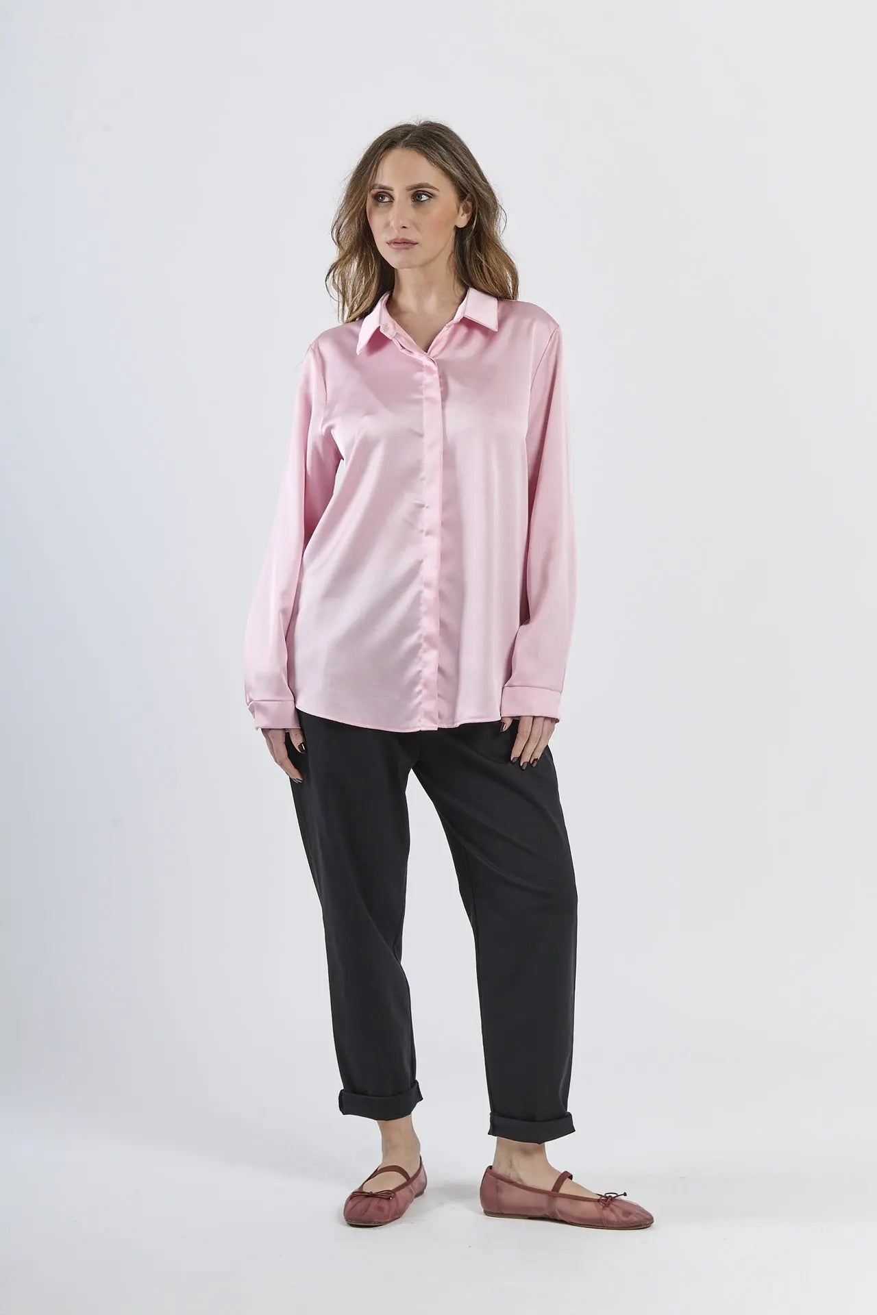 Camicia rosa in seta con colletto, abbinata a pantaloni beige.