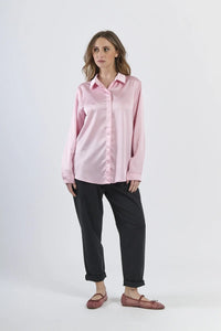 Camicia rosa in seta con colletto, abbinata a pantaloni beige.