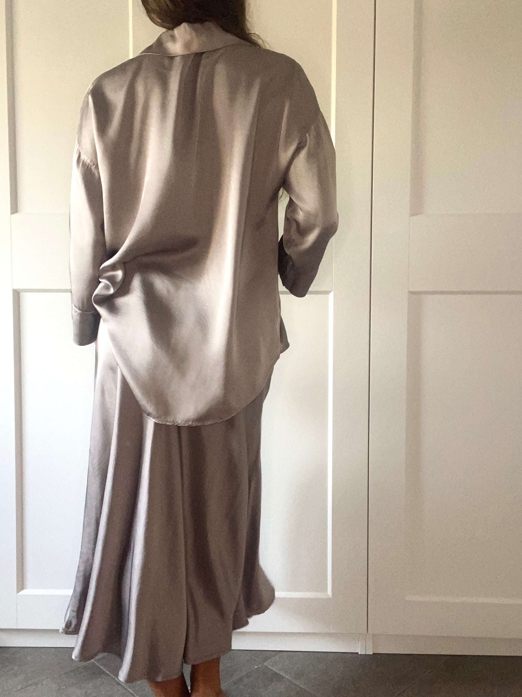 Completo da donna in seta beige: camicia a colletto e gonna lunga, modello posa con mano sulla vita.