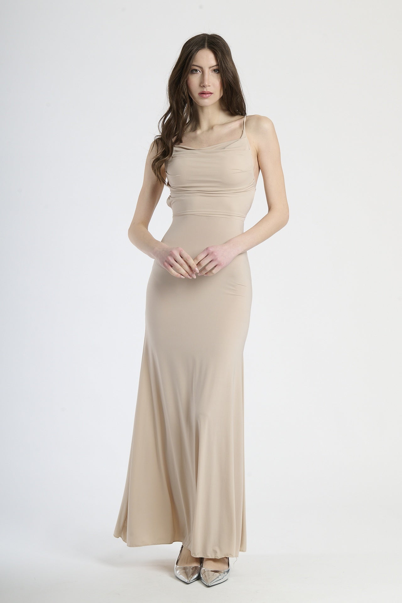 Donna con abito beige a spalline sottili, calore neutro e eleganza sobria.