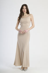Donna con abito beige a spalline sottili, calore neutro e eleganza sobria.