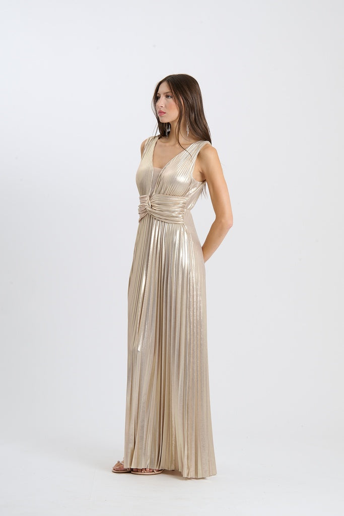 Donna con abito da sera beige, lungo, senza maniche, plissé e scollatura a V, in uno studio fotografico.
