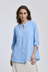 Donna con camicia azzurra a bottoni, collo a V, maniche 3/4, stile casual e fresco