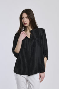 Donna con camicia nera a bottoni, collo a V, maniche 3/4, stile elegante e intenso