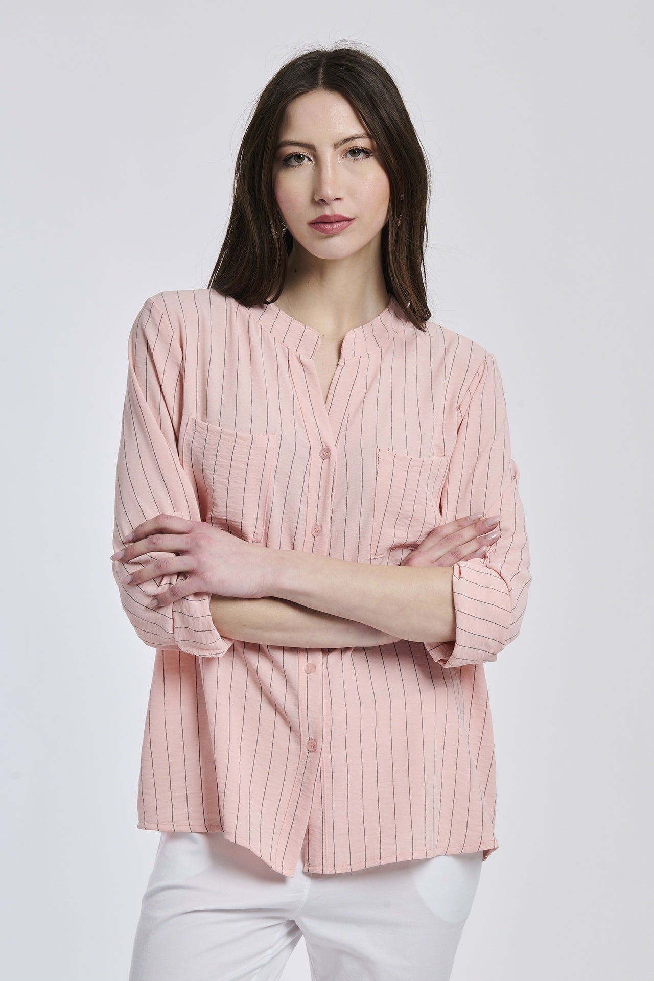 Donna con camicia rosa a bottoni, collo rotondo, maniche lunghe rimboccate