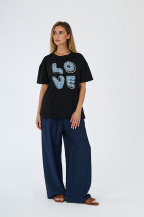 Donna con t-shirt  nero e pantaloni larghi scuri