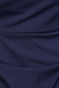 Donna indossa un abito navy senza maniche, lunghezza midi, con nodo al petto, look elegante.

