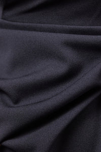 Donna indossa un abito nero senza maniche, lunghezza midi, con nodo al petto, look elegante.