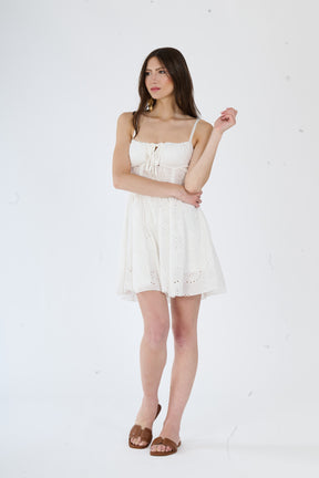 Elegante abito bianco in pizzo con taglio avvolgente e snodo decorativo, per un look raffinato.