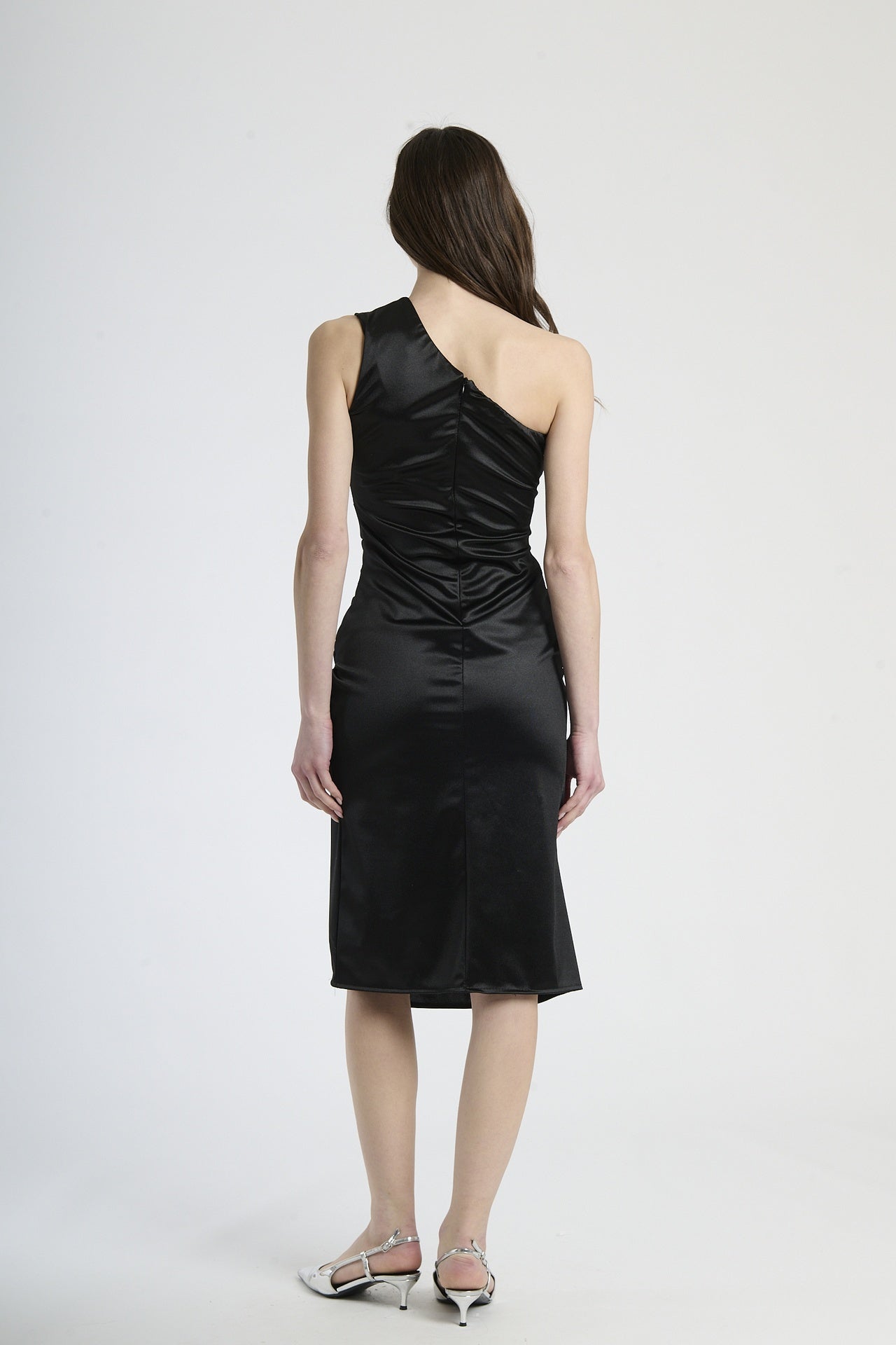 Modella indossa abito nero con plissé, stile iconico per serate notturne.