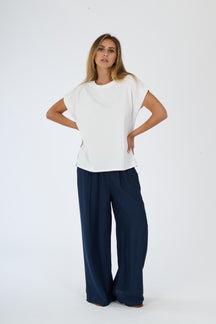 T-shirt beige stampata e pantaloni bianchi larghi su una figura femminile