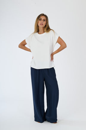 T-shirt beige stampata e pantaloni bianchi larghi su una figura femminile