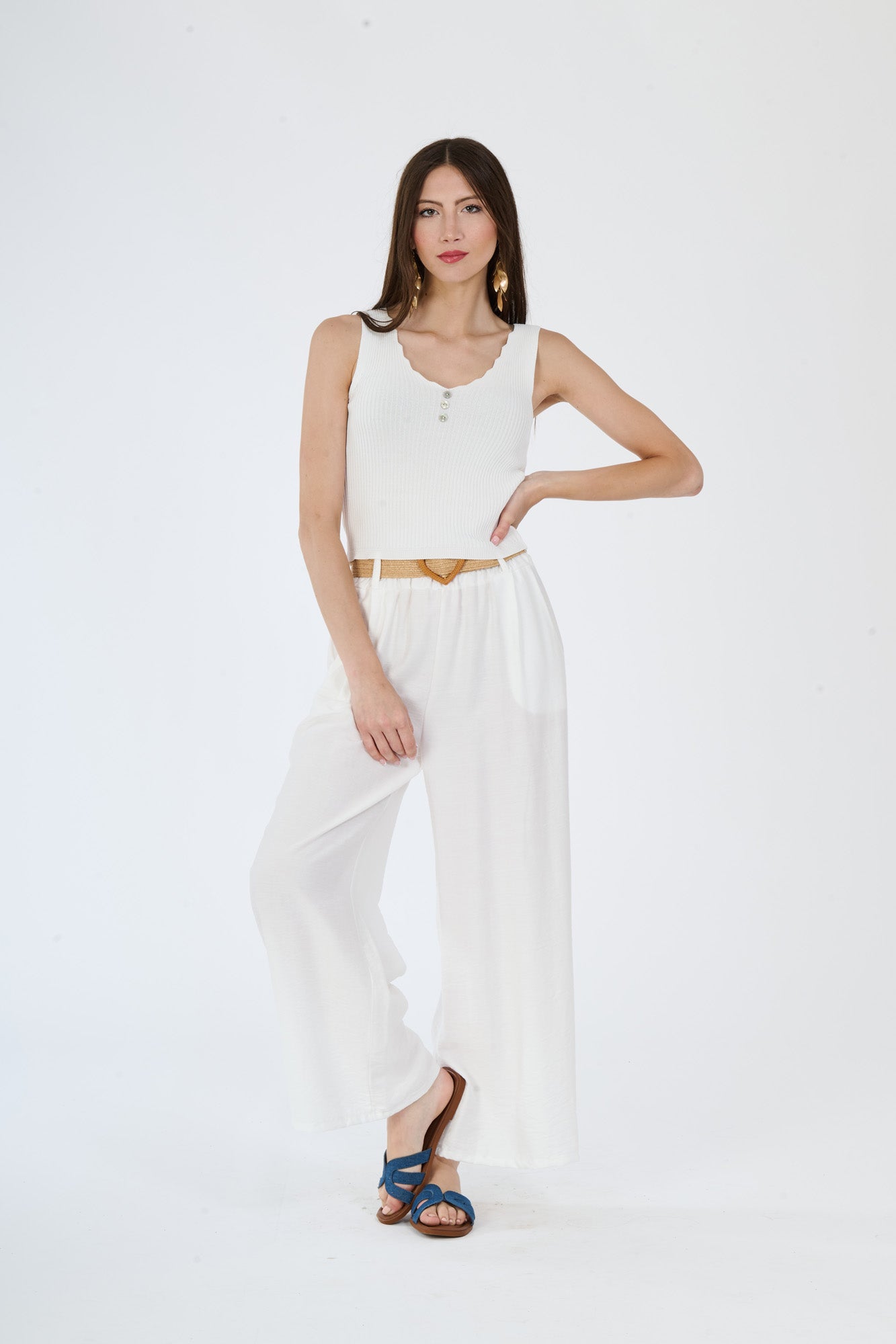 Top bianco senza maniche e pantaloni larghi bianchi, un set che evoca freschezza e semplicità stilistica.