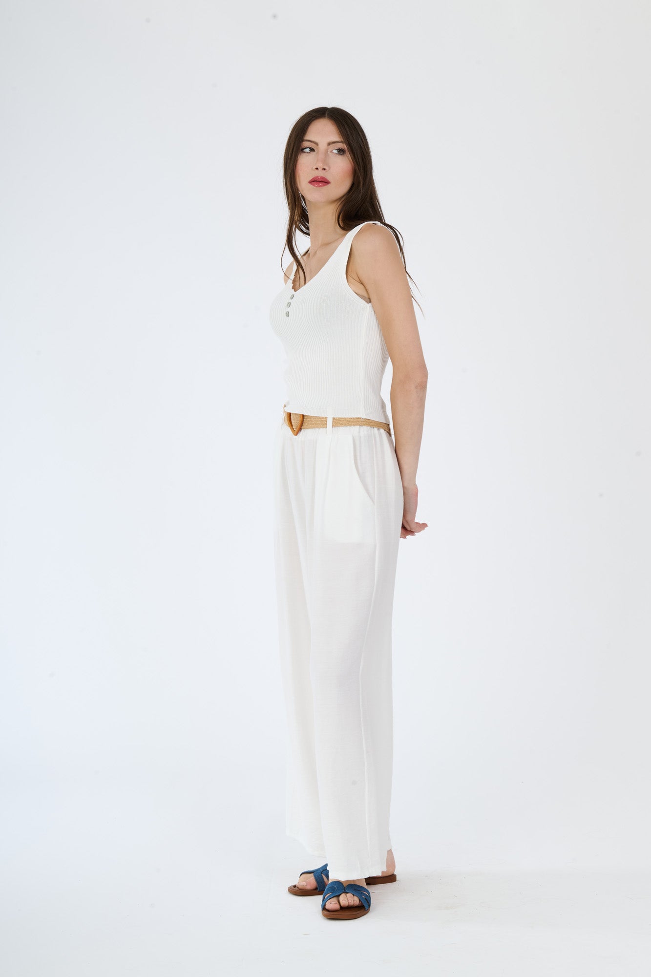Top bianco senza maniche e pantaloni larghi bianchi, abbinamento monocromatico con cintura in contrasto, stile moderno e pulito.