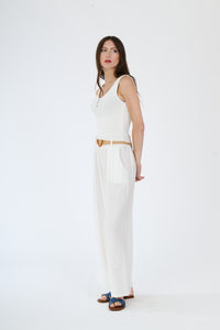 Top bianco senza maniche e pantaloni larghi bianchi, abbinamento monocromatico con cintura in contrasto, stile moderno e pulito.