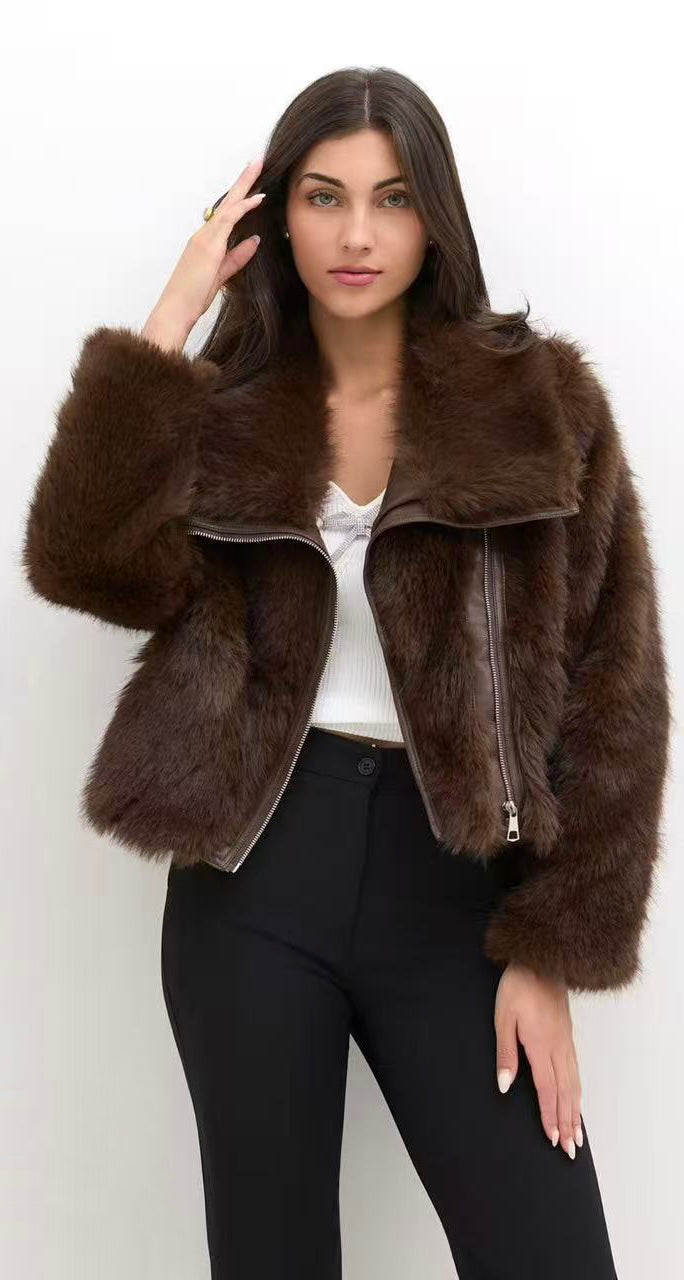 Una modella indossa una giacca in pelliccia marrone scura, un top bianco e pantaloni neri, posando su sfondo bianco.