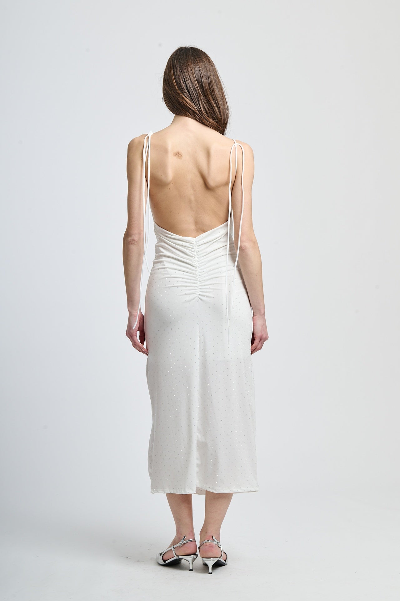 Vestito bianco a corpo con dettagli in raso, dando un tocco di lusso.